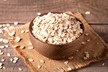 Ahşap bir arka planda tahta bir kasede çiğ yulaf. Organik gıda konsepti. 