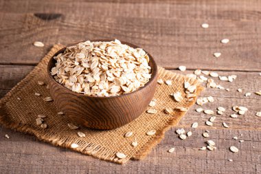 Ahşap bir arka planda tahta bir kasede çiğ yulaf. Organik gıda konsepti. 