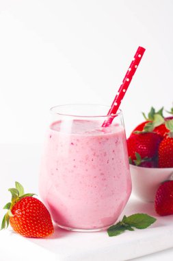 Beyaz arka planda bir bardak taze çilekli smoothie. Yaz içeceği, milkshake ve ferahlatıcı organik konsept..
