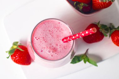 Beyaz arka planda bir bardak taze çilekli smoothie. Yaz içeceği, milkshake ve ferahlatıcı organik konsept..
