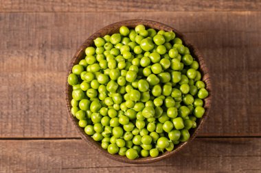 Tahta masadaki bir kasede taze bezelye ve kabuklar. Sebzeli sağlıklı yiyecek..  