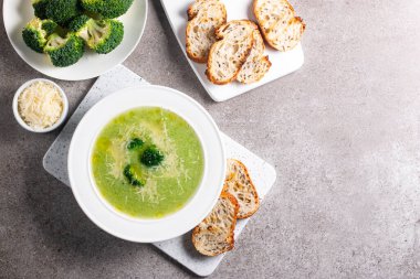 Sıcak ve rahatlatıcı kremalı brokoli çorbası bir kasede servis edilir, parmesan peyniri ve kızarmış ekmekle süslenir..