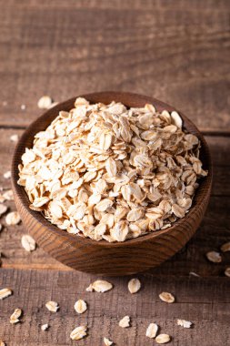 Ahşap bir arka planda tahta bir kasede çiğ yulaf. Organik gıda konsepti. 