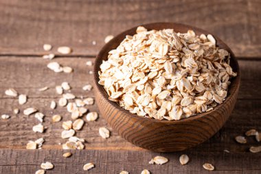 Ahşap bir arka planda tahta bir kasede çiğ yulaf. Organik gıda konsepti. 