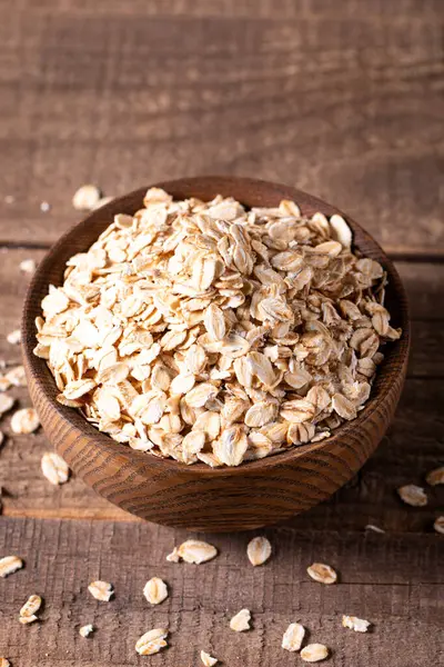 Ahşap bir arka planda tahta bir kasede çiğ yulaf. Organik gıda konsepti. 