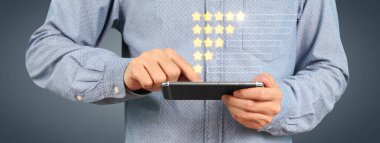 Akıllı telefon aygıtı tutan ve beş yıldız derecelendirme geri besleme simgesi ile ekrana dokunan adam