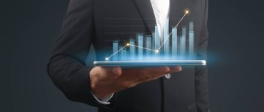 İşadamı, elinde tabletle iş yerinde grafik büyümesi ve grafik artışı planlıyor