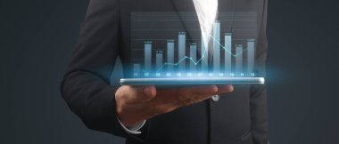 İşadamı, elinde tabletle iş yerinde grafik büyümesi ve grafik artışı planlıyor