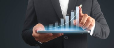 İşadamı, elinde tabletle iş yerinde grafik büyümesi ve grafik artışı planlıyor