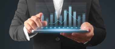 İşadamı, elinde tabletle iş yerinde grafik büyümesi ve grafik artışı planlıyor