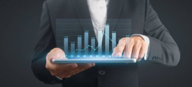 İşadamı, elinde tabletle iş yerinde grafik büyümesi ve grafik artışı planlıyor