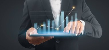 İşadamı, elinde tabletle iş yerinde grafik büyümesi ve grafik artışı planlıyor