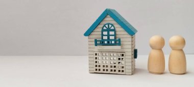 Beyaz arka planda minyatür bir evin yanına ahşap biblolar inşa ediyoruz.