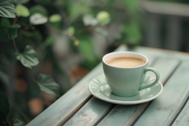 Taze demlenmiş kahve, yemyeşil bir bahçe ortamında, ahşap bir masada servis edilir. Sabah molası için huzurlu ve rahatlatıcı bir atmosfer yaratır..