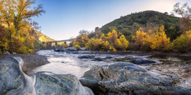 Korsika 'daki Barchetta yakınlarındaki Torrent de Cipetto' daki Pont d 'Albano demiryolu köprüsünün altından geçen sonbahar yeşillikleri ve kayaların panoramik manzarası.