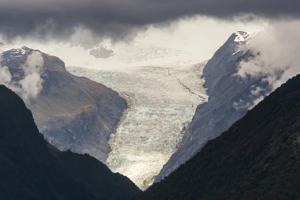 Fox Glacier on the west coast of the South Island of New Zealand appearing beneath the clouds
