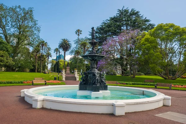 Albert Park, Auckland, New Zealand - December 28th 2022: Fountain in Albert Park in the city of Auckland, New Zealand with Jacaranda and palm trees in the background