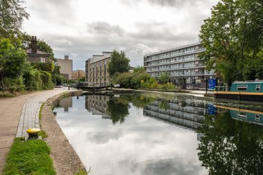 Regent 's Row, Regent' s Canal, Hackney, Londra, İngiltere - 29 Temmuz 2023: Regent 's Canal' ın sakin sularına ve Doğu Londra, Hackney 'deki Regent' s Row 'un kilitli kapılarına yansıyan binalar.
