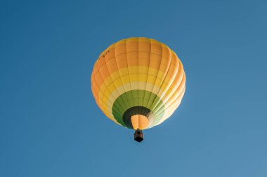 Rocamadour, Fransa - 24 Eylül 2023: Fransa 'da düzenlenen Montgolfiades de Rocamadour balon festivali sırasında sarı, turuncu ve yeşil bir sıcak hava balonu tepemizden geçer