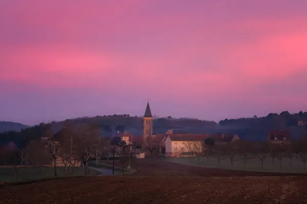 Pink and purple dawn breaking at sunrise over the rural village of Nabirat in the Dordogne region of France