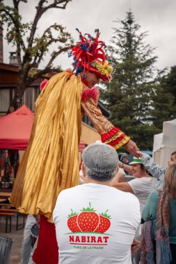 Nabirat, Nouvelle-Aquitaine, Fransa - 12 Mayıs 2024: Üzerinde yıllık çilek fuarı logosu olan bir adam, Foire de la Fraise, Fransa 'nın Dordogne bölgesindeki Nabirat' ta bir stilt walker olarak toplanıyor ve kalabalığı eğlendiriyor