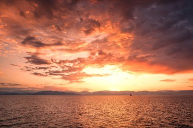 Geleneksel bir üç direkli gemi, Akdeniz 'i aydınlatan Korsika adasının engebeli kıyı şeridi üzerinde güzel bir altın gün doğumuna karşı siluet oluşturdu.