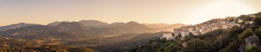 Sabahın erken saatlerindeki panoramik manzara vadiyi sarıyor ve Korsika 'nın Sartene kasabasının arkasındaki uzak Bavella dağlarını.