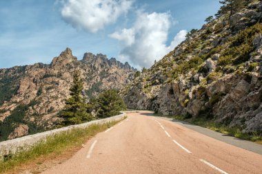 Aiguilles de Bavella 'ya doğru giden D268 yolu, Korsika' nın merkezinde çam ormanlarıyla çevrili kayalık dağ tepeleri gibi bir iğne.