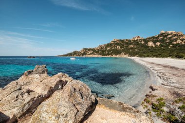 Yachts in the bay at Roccapina beach on the south west coast of Corsica overlooked by the Genoese Tour de Roccapina and Lion of Roccapina, a rocky outcrop in the shape of a lion clipart