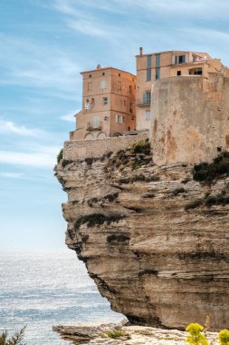 Korsika 'daki Bonifacio kalesinde deniz ve hava koşulları altında kireçtaşı kayalıklara tünemiş evler.