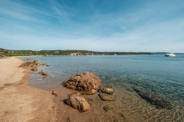 Akdeniz adası Korsika 'nın güney doğu kıyısındaki Gurgazu köyünün yakınındaki Plage de Gandina körfezinde demirlemiş tekneli terk edilmiş kumlu bir sahil.