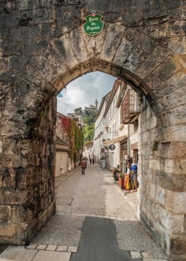 Rocamadour, Lot, France - 23rd September 2024: The 13th century Porte de Figuier leading to Rue Roland le Preux, the main street of the medieval village of Rocamadour in the Lot region of France, with the chateau in the distance clipart