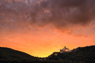 Castelnaud-la-Chapelle, Dordogne, France - October 24th 2024: Orange glow as the sun sets behind Chateau de Castelnaud at Castelnaud-la-Chapelle in the Dordogne region of France clipart