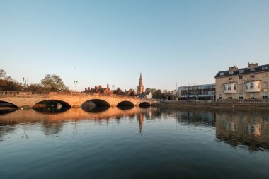 Bedford, İngiltere - 8 Nisan 2025: St Paul Kilisesi ve Kuğu Oteli 'nin kulesiyle İngiltere' nin Bedfordshire kentindeki Büyük Ouse kasabasının üzerindeki kasaba köprüsünde sabah güneşi