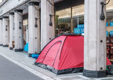 Londra, İngiltere - 28 Nisan 2025: Evsizler tarafından kullanılan çadırlar Londra 'daki Tottenham Court Yolu' nun kaldırımında Heals adlı bir mobilya mağazasının önünde kurulmuştur.