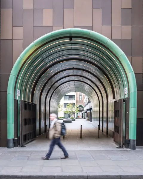 Londra, İngiltere - 28 Nisan 2025: Bir adam Fitzrovia, Londra 'daki Rathbone Meydanı' na giden kemerli tünelin yanından geçiyor