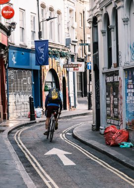 Londra, İngiltere - 28 Nisan 2025: Sırt çantalı bir bisikletçi Londra 'nın merkezinde Hanway Caddesi boyunca koşuyor