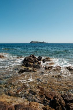 Akdeniz adası Korsika 'daki Cap Corse' un kuzey ucundaki kayalık kıyılara vuran dalgalar Giraglia adası kadar uzaktır.