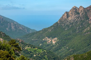 Korsika adasının batı kıyısındaki Ota köyünün arkasında Capu d 'Ota tepesi ve Akdeniz uzanır.