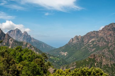Korsika adasının batı kıyısı yakınlarındaki Ota köyünde Capu d 'Ota ve Capu d' Orto 'nun yüksek tepeleri ve Akdeniz uzaklıklarında yer alır.