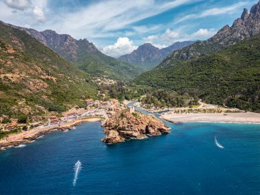 Genoise kulesinin kayalık bir çıkıntıdaki havadan görünüşü ve Akdeniz 'in batı kıyısındaki Porto sahilinde arkasında dağlarla birlikte Korsika adasının