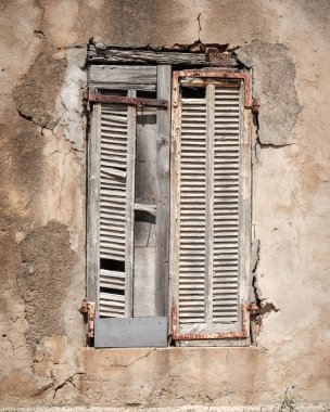Akdeniz 'in Korsika adasındaki Girolata' da dökülen eski bir binanın beyaz boya ve paslı parantezleriyle kaplı eski bir ahşap pencere kepengi.