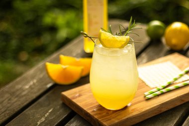 Limonlu misket limonlu ev yapımı limonata ve doğadaki ahşap masada meyve süslemeli bir bardak.