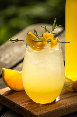 Limonlu misket limonlu ev yapımı limonata ve doğadaki ahşap masada meyve süslemeli bir bardak.