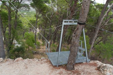 Dağdan metal bir kabloyla inmiş. Halatla kaymak doğada çok eğlenceli bir fotoğraftır.