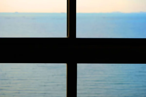View of the ocean from inside a window with sunset.