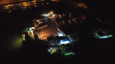 Balıkçı teknelerinden kargo kamyonlarına yükleme. Limandaki balıkçı teknelerinin ışıkları altında çalışan balıkçılar. Balıkçılık endüstrisi gece hayatı için idealdir. İnsan işçiler gece yarısı limanında hareket edebilirler.