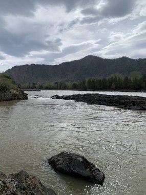 Nehir yemyeşil vadide yavaşça akar, huzurlu ve huzurlu bir atmosfer yaratır. Açık mavi-yeşil su çevredeki tepelerin güzelliğini yansıtır..