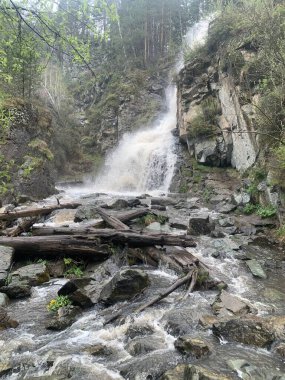 Bereketli bir ormanda çarpıcı bir şelale, kayaların üzerinde çağlayan su büyüleyici bir görüntü yaratıyor. Devrilen ağaçlar sahneye heyecan katar, güzelliği ve macerayı harmanlarlar..