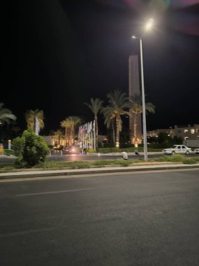 Sharm el Sheikh, Mısır 'da büyük bir dikilitaş ve palmiye ağaçlarının bulunduğu bir otel girişi. Sokak lambası sokakta sıcak bir parıltı yayar ve akşam sıcak bir atmosfer yaratır..